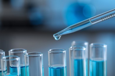 Photo of Dripping liquid from pipette into test tube in laboratory, closeup