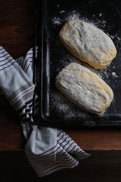 Photo of Raw dough for ciabatta and flour on wooden table