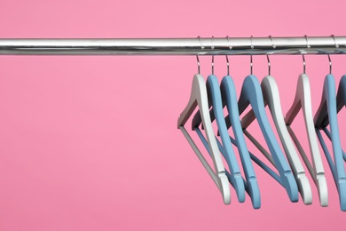 Photo of Empty clothes hangers on metal rail against color background. Space for text