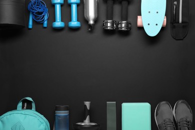 Frame made of different sports equipment on black background, flat lay. Space for text