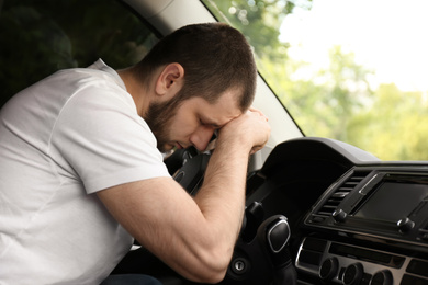 Photo of Tired man sleeping on steering wheel in his car