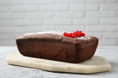 Photo of Tasty chocolate sponge cake with powdered sugar and currant on light grey textured table