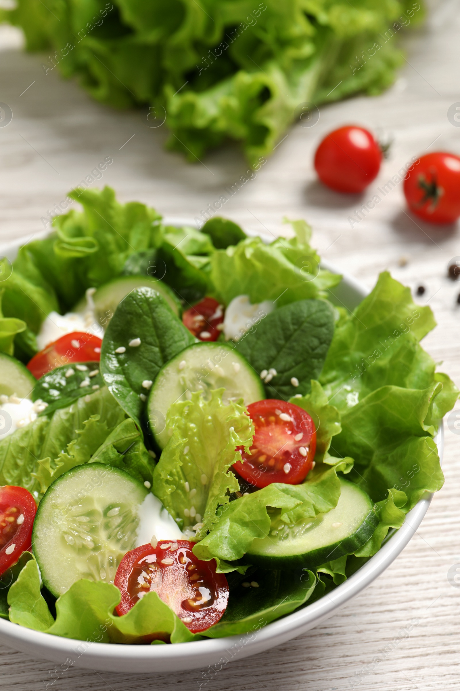 Photo of Delicious salad in bowl on white wooden table, closeup