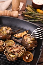 Photo of Tasty grilled artichokes on table, closeup view