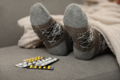 Mature woman and cold remedies on sofa, closeup. Dangerous virus