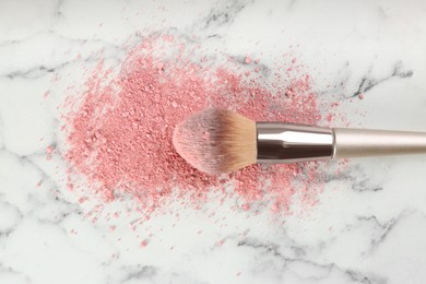 Photo of Makeup brush and scattered blush on white marble table, top view