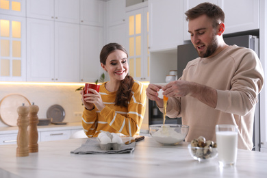 Photo of Lovely young couple cooking dough together in kitchen