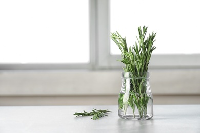 Photo of Jar with fresh rosemary twigs on table