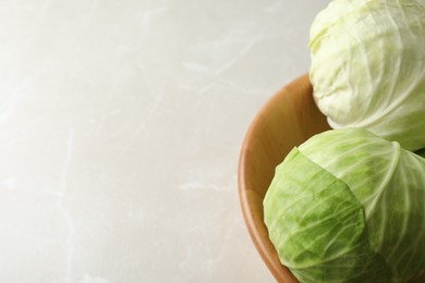 Photo of Ripe white cabbage on light marble table, closeup. Space for text