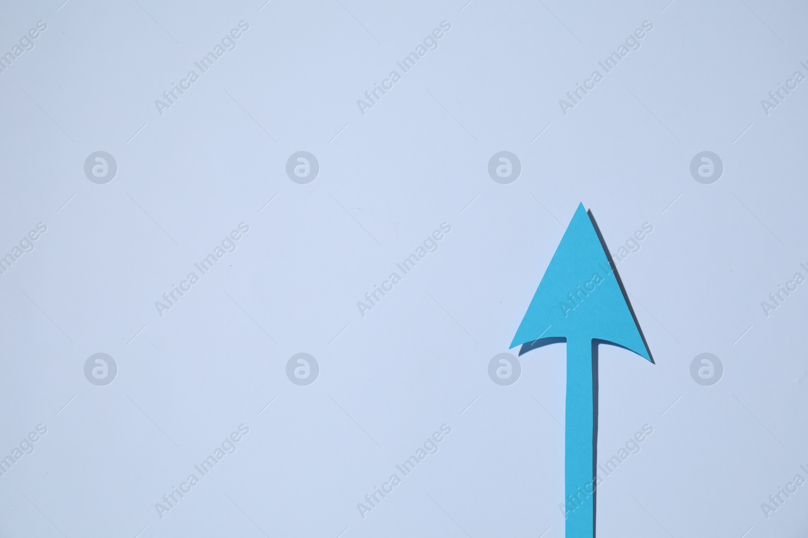 Photo of Light blue paper arrow on white background, top view. Space for text