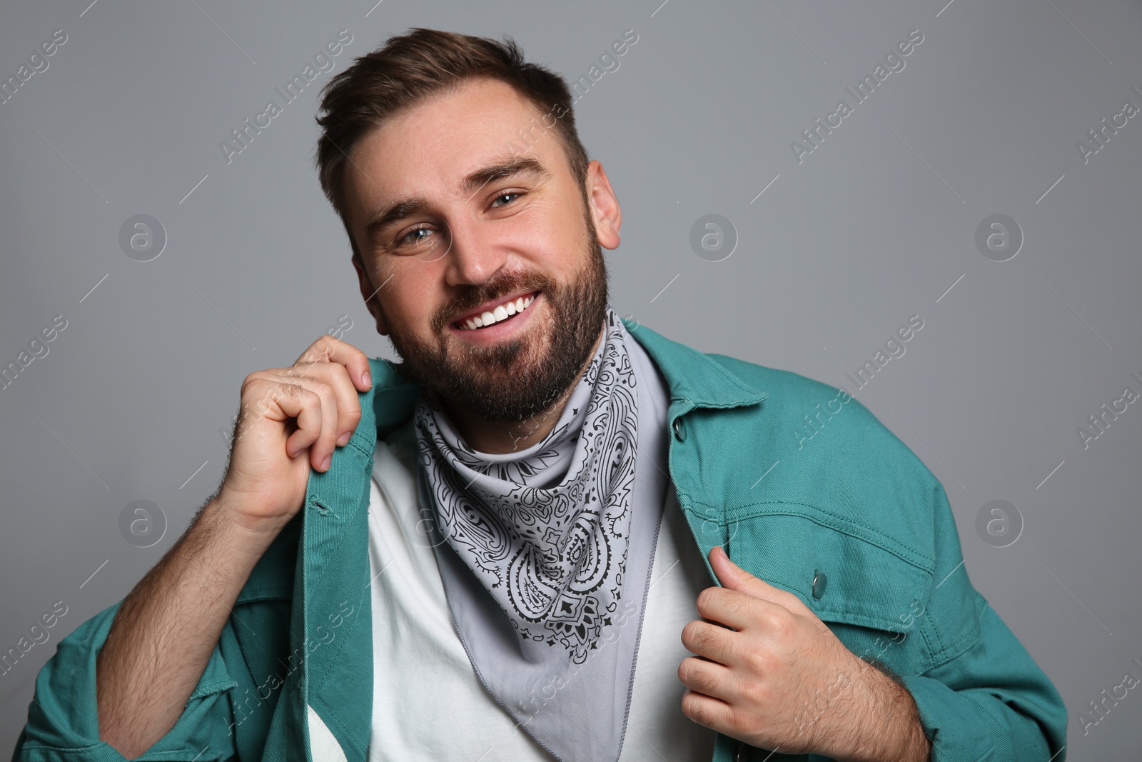 Photo of Fashionable young man in stylish outfit with bandana on grey background