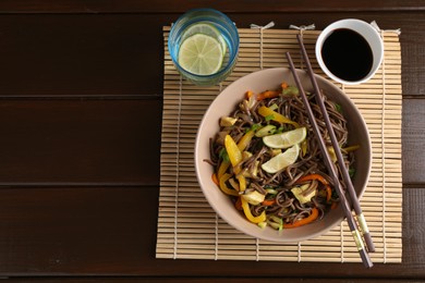 Photo of Stir-fry. Delicious cooked noodles with chicken and vegetables in bowl served on wooden table, flat lay. Space for text