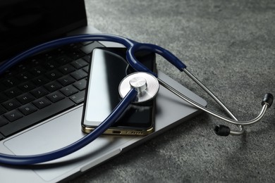 Modern electronic devices and stethoscope on grey table