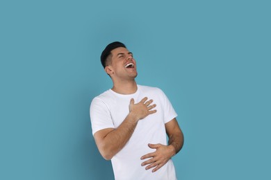 Photo of Handsome man laughing on light blue background. Funny joke