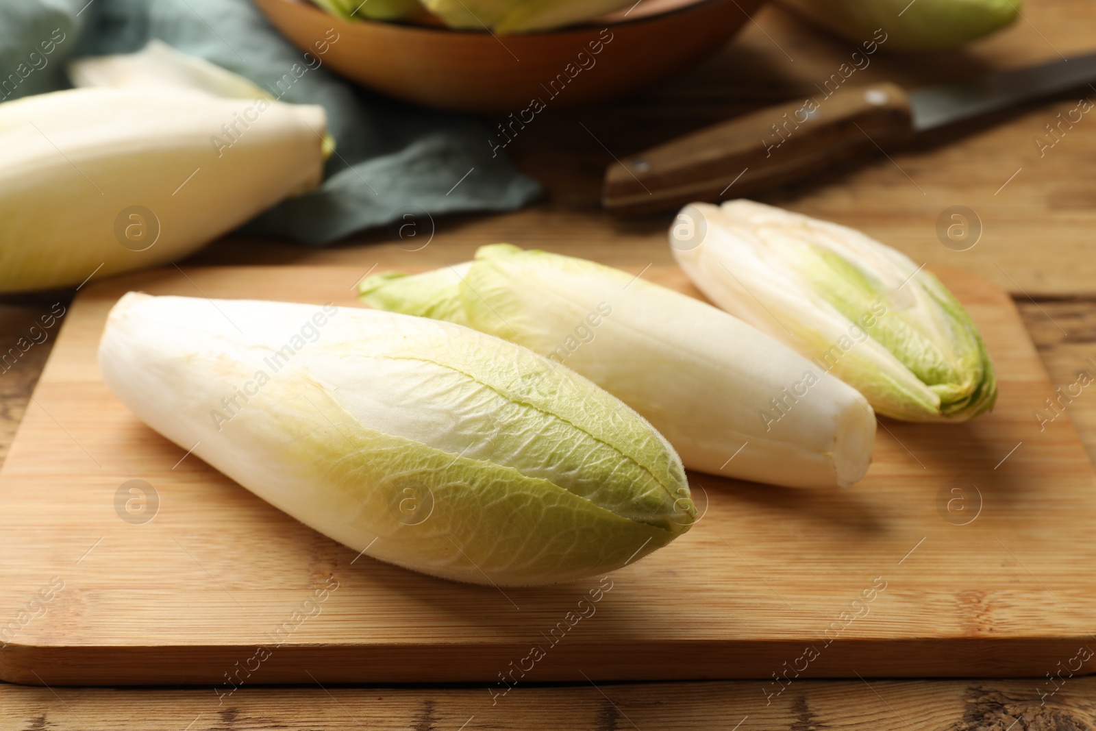 Photo of Fresh raw Belgian endives (chicory) on wooden table, closeup