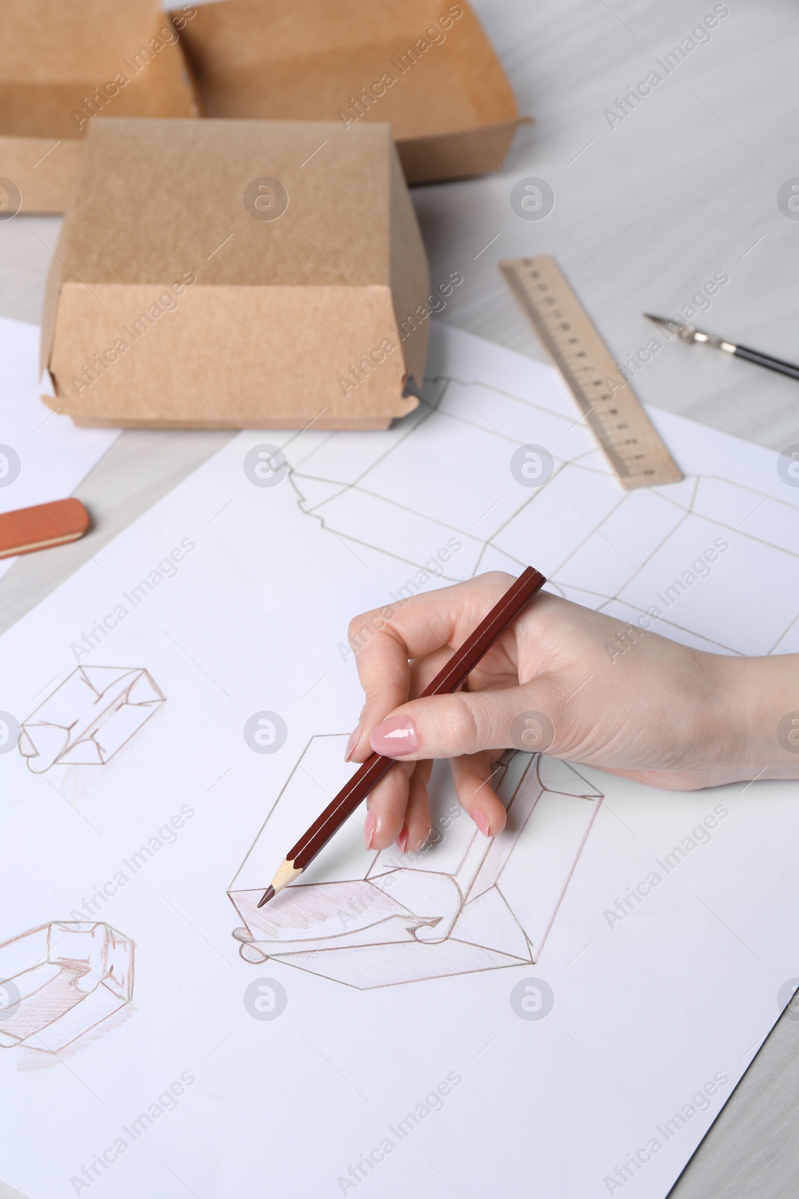 Photo of Woman creating packaging design at light wooden table, closeup