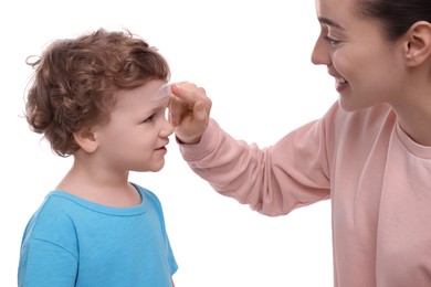 Mother applying ointment onto her son`s forehead on white background
