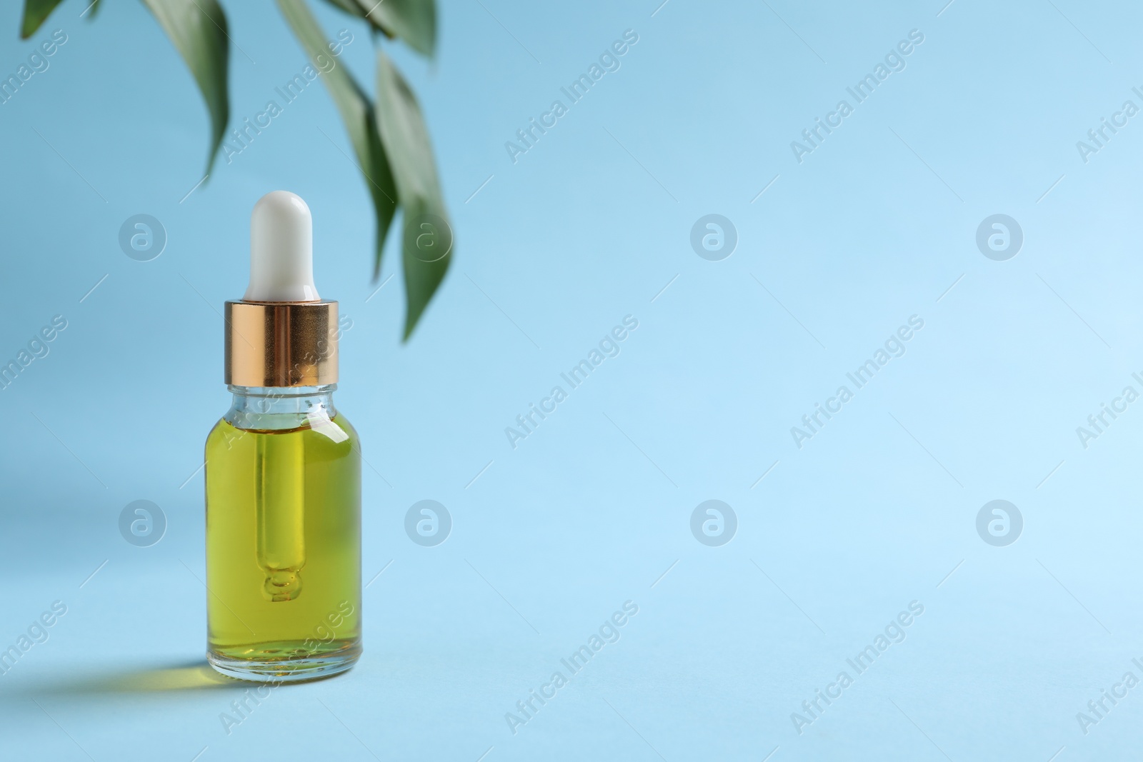 Photo of Bottle with cosmetic oil on light blue background. Space for text
