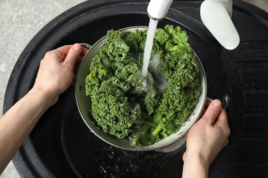 Photo of Woman washing fresh kale leaves over sink, closeup