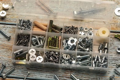 Photo of Organizer with many different fasteners on rustic wooden table, above view