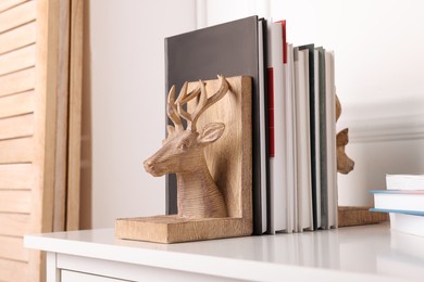 Photo of Wooden deer shaped bookends with books on table indoors