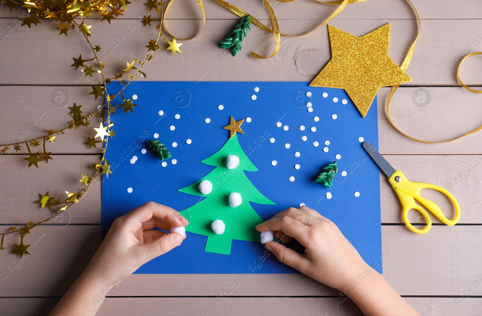 Photo of Little child making Christmas card at wooden table, top view