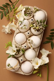 Photo of Festive composition with eggs and floral decor on brown background, flat lay. Happy Easter