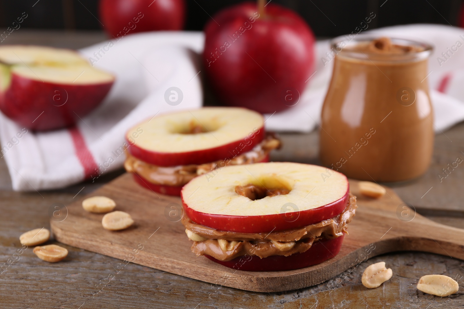 Photo of Slices of fresh apple with peanut butter and nuts on wooden table, closeup. Space for text