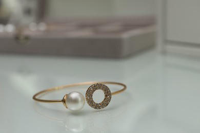 Elegant golden bracelet with pearl and diamonds on white table