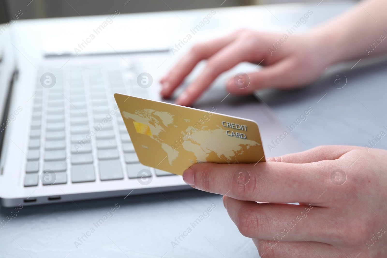 Photo of Online payment. Woman with laptop and credit card at white table, closeup