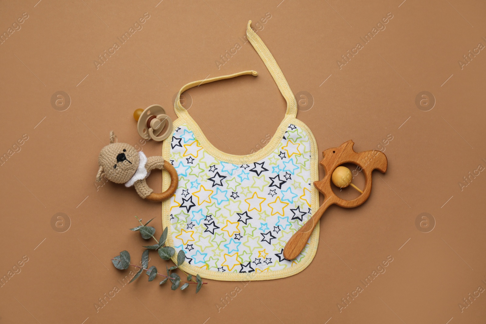 Photo of Flat lay composition with baby accessories and bib on brown background