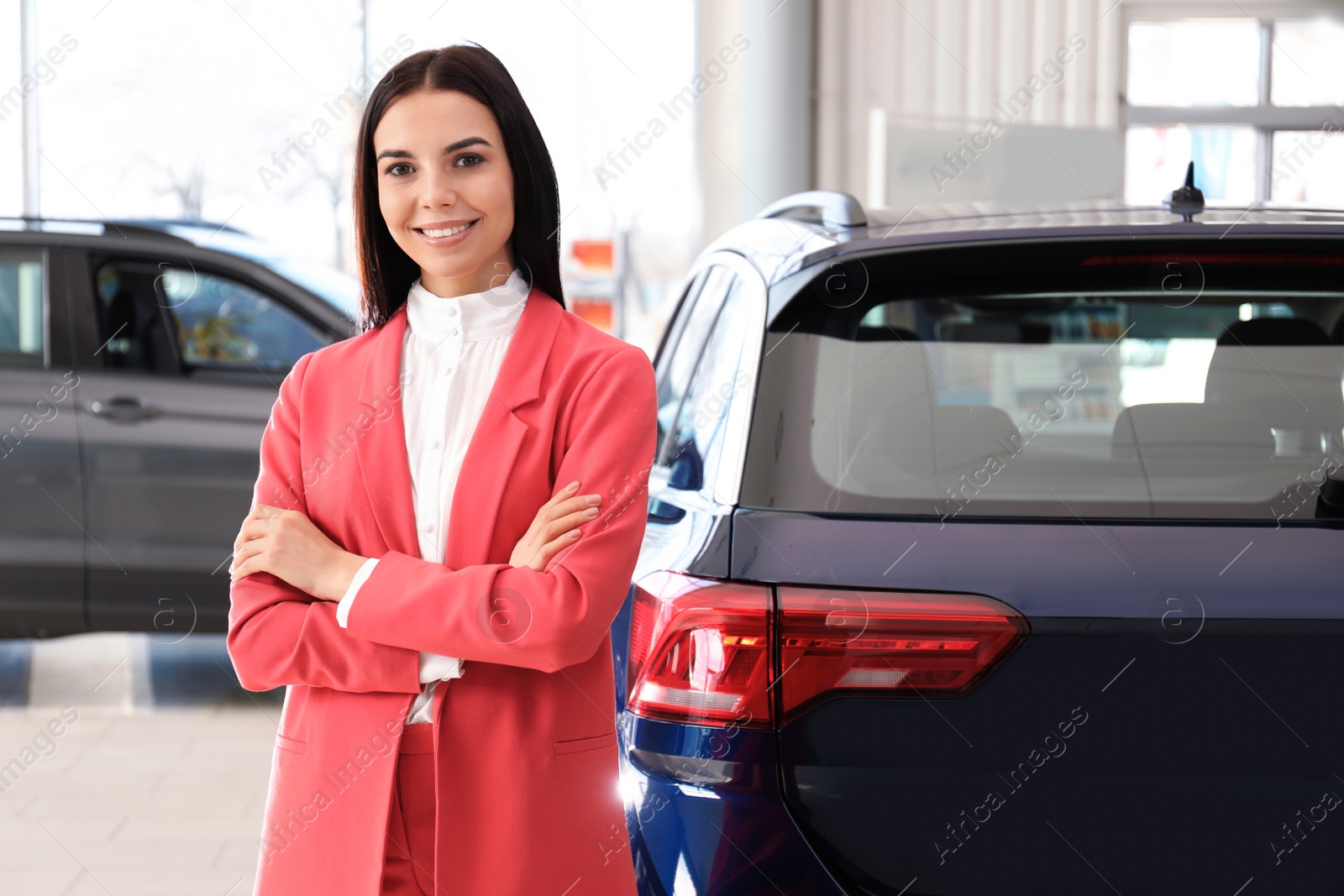 Photo of Happy young saleswoman in modern car salon