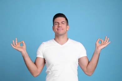 Photo of Man meditating on light blue background. Stress relief exercise