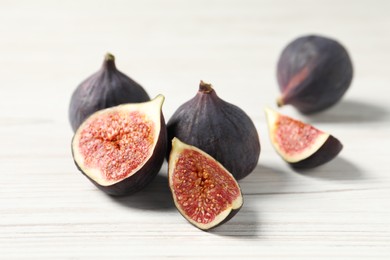 Whole and cut ripe figs on white wooden table, closeup