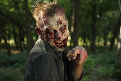 Photo of Scary zombie with bloody face outdoors. Halloween monster