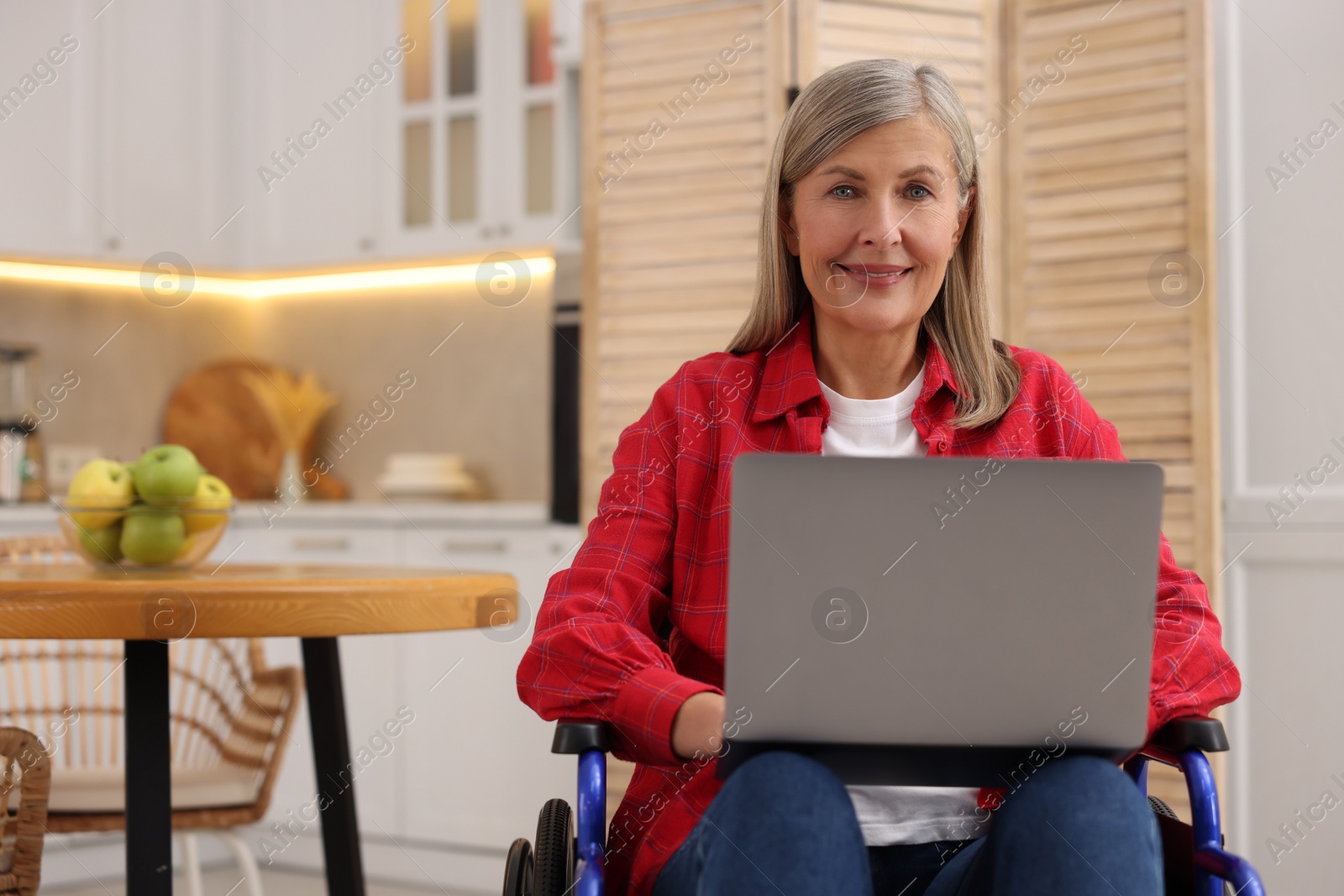 Photo of Woman in wheelchair using laptop at home