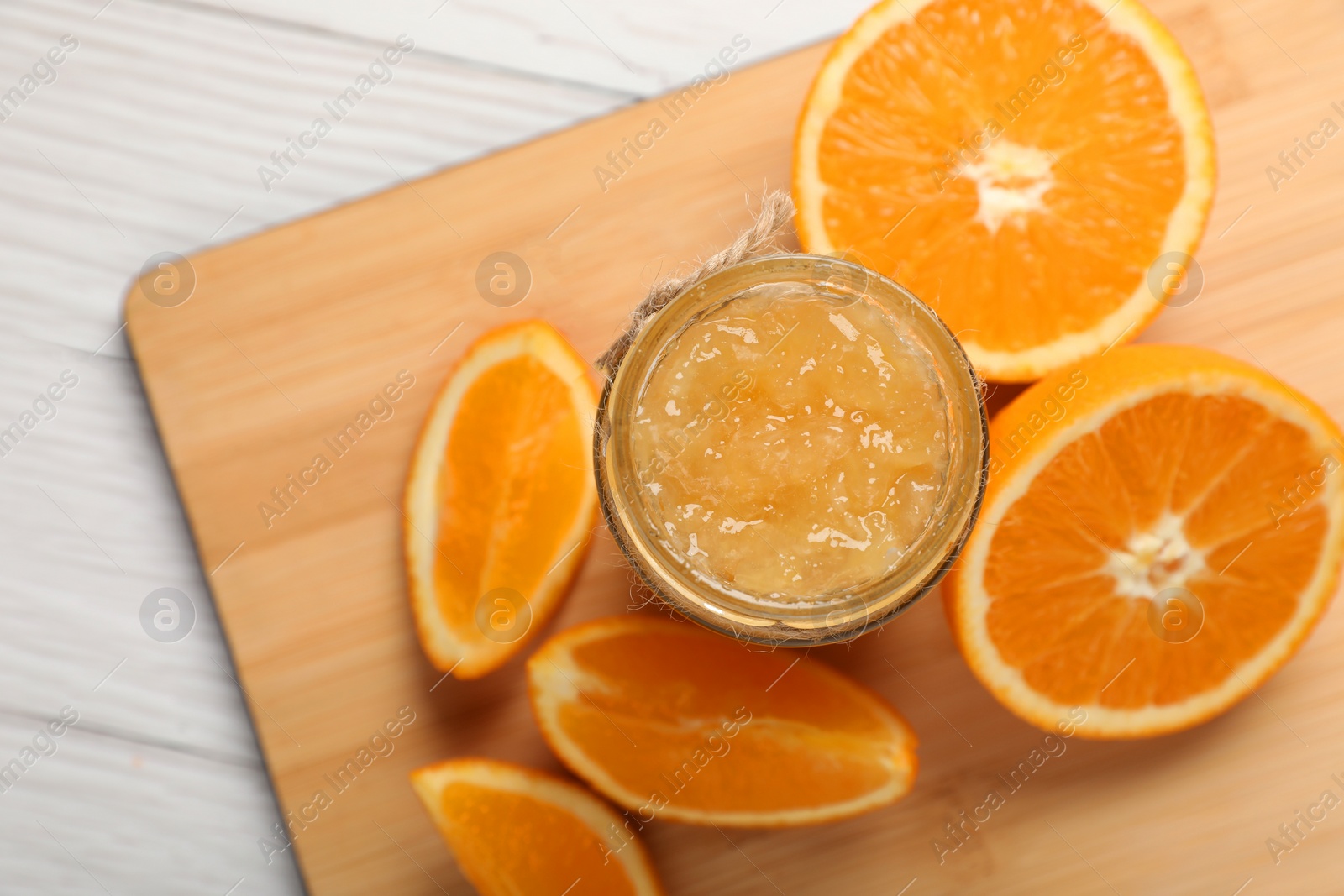 Photo of Jar of delicious orange jam and fresh fruits on white wooden table, top view