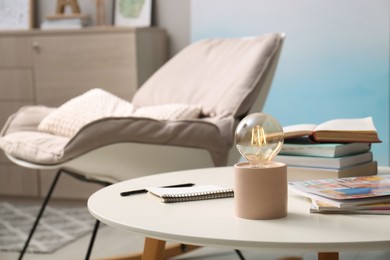 Modern night lamp, books and magazines on table in room. Space for text