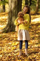 Girl with cute Maltipoo dog in autumn park