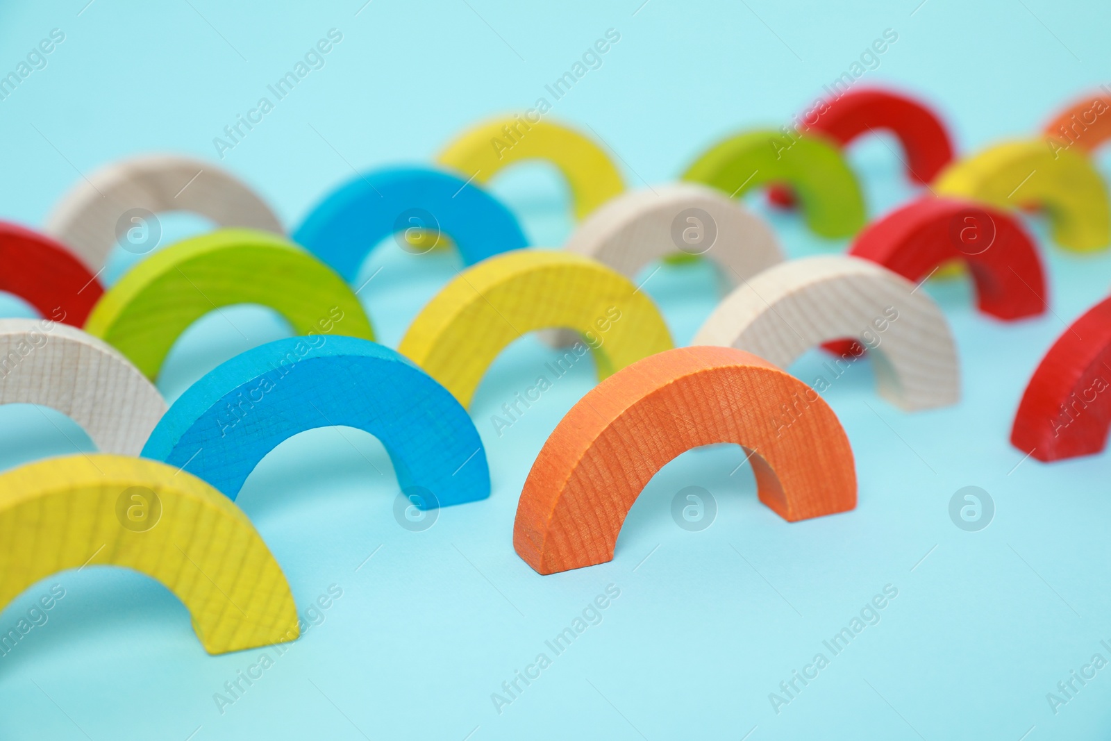 Photo of Colorful wooden pieces of playing set on light blue background. Educational toy for motor skills development