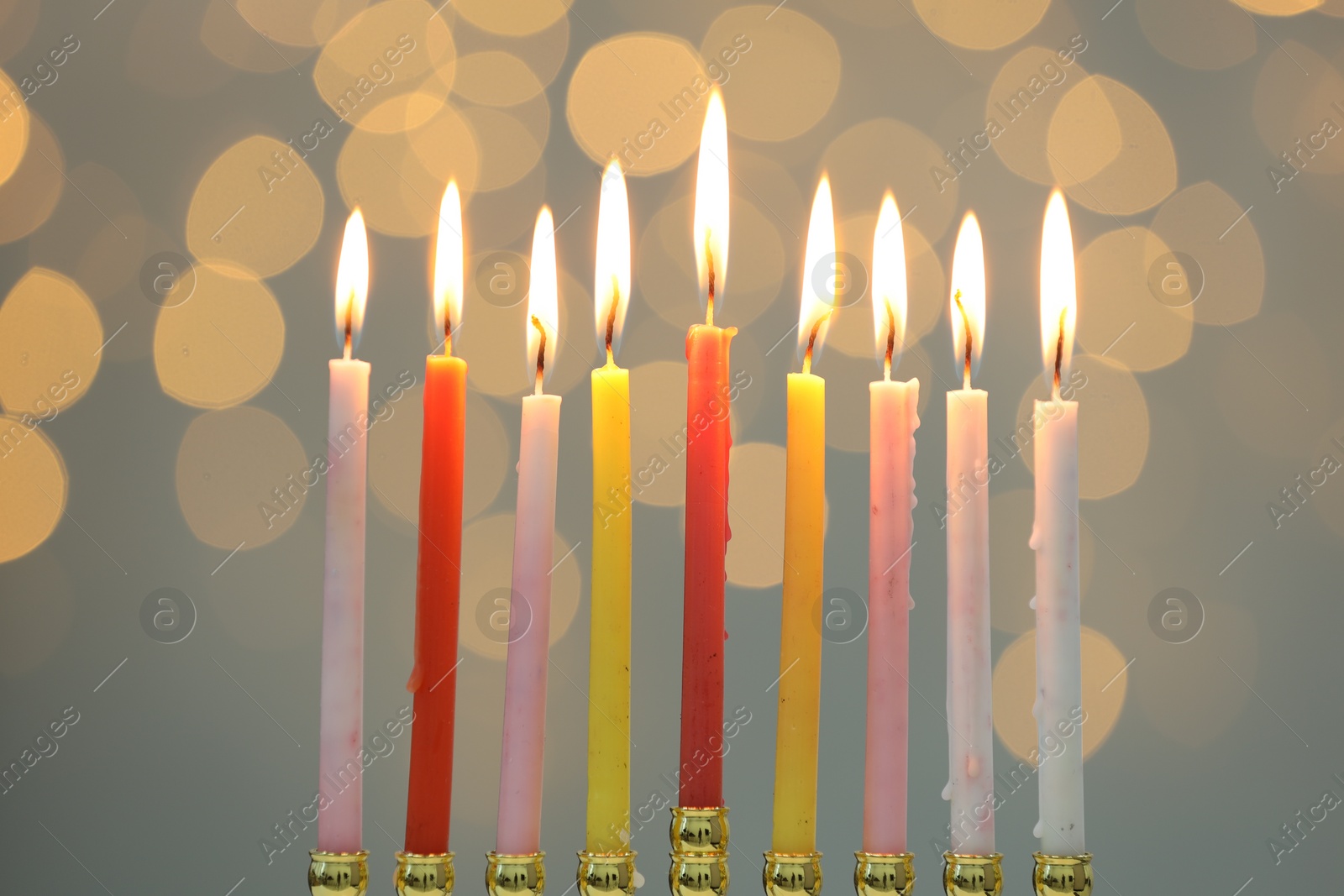 Photo of Hanukkah celebration. Menorah with burning candles against blurred lights