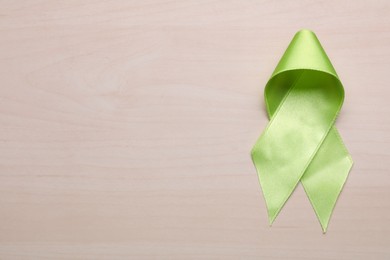 Photo of World Mental Health Day. Green ribbon on wooden background, top view with space for text