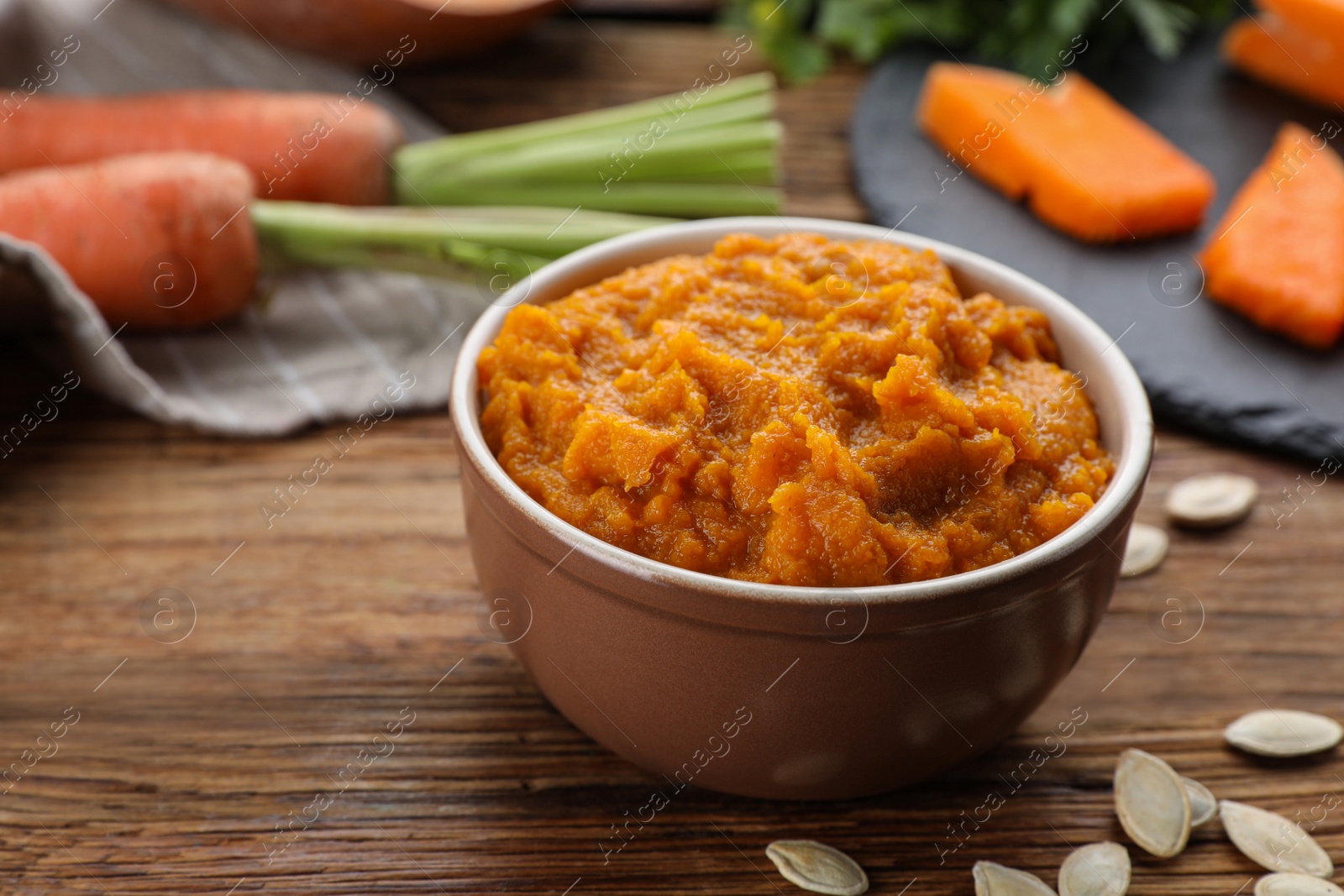 Photo of Bowl with tasty puree and ingredients on wooden table, closeup