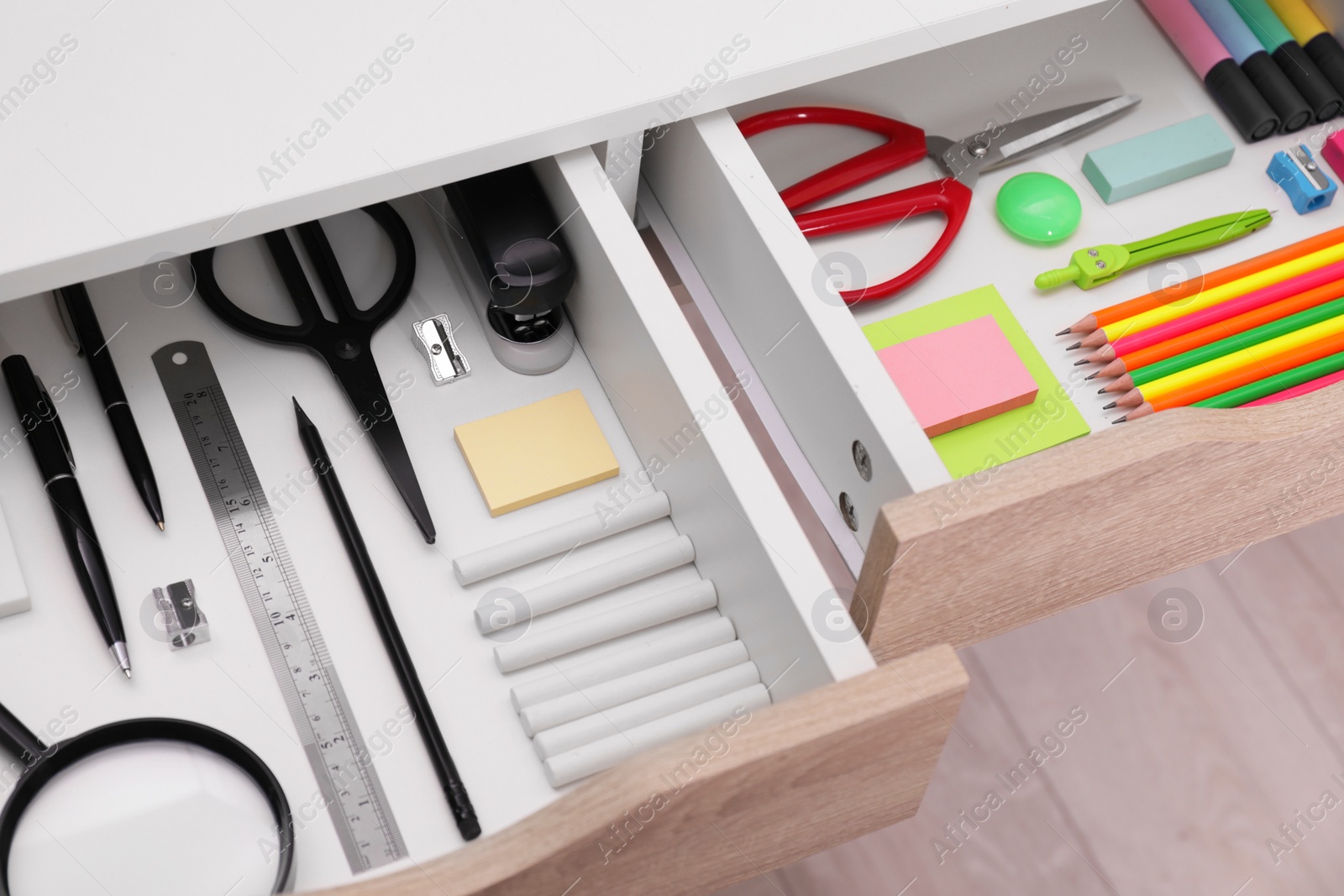 Photo of Office supplies in open desk drawers, above view