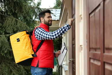 Courier with thermo bag and clipboard knocking on customer's house. Food delivery service