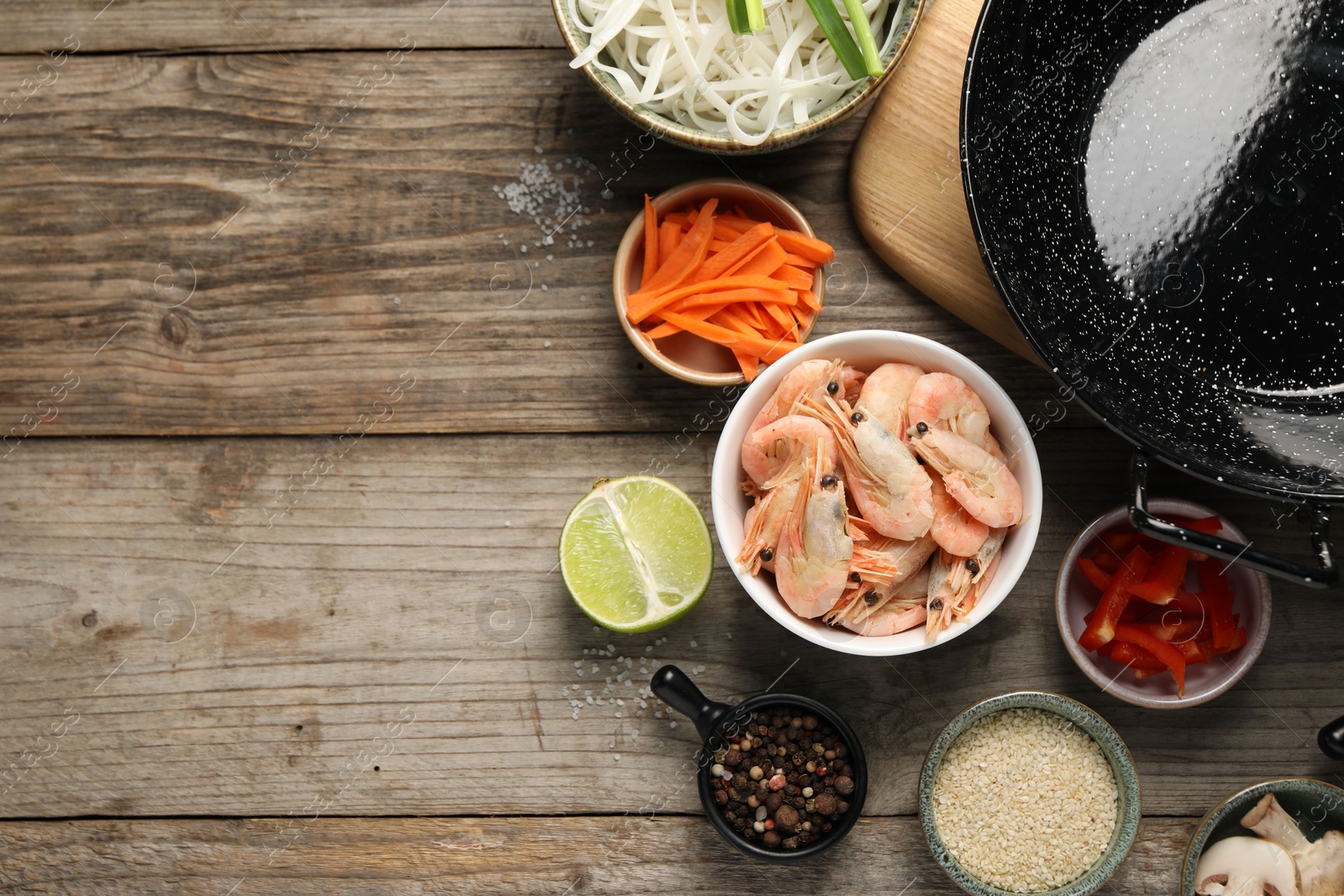 Photo of Flat lay composition with black wok, spices and products on wooden table. Space for text