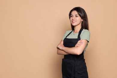 Photo of Happy professional hairdresser in apron against pale orange background. Space for text