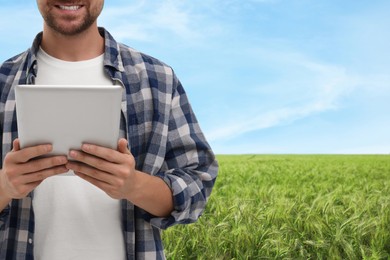 Farmer with tablet computer in field, closeup. Harvesting season