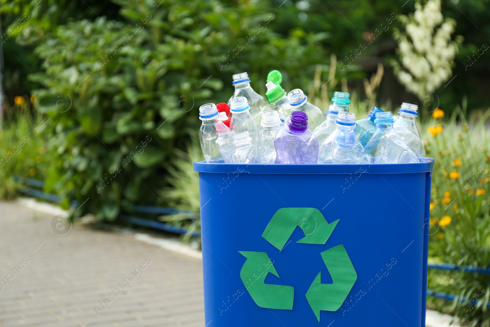 Photo of Many used bottles in trash bin outdoors, space for text. Plastic recycling