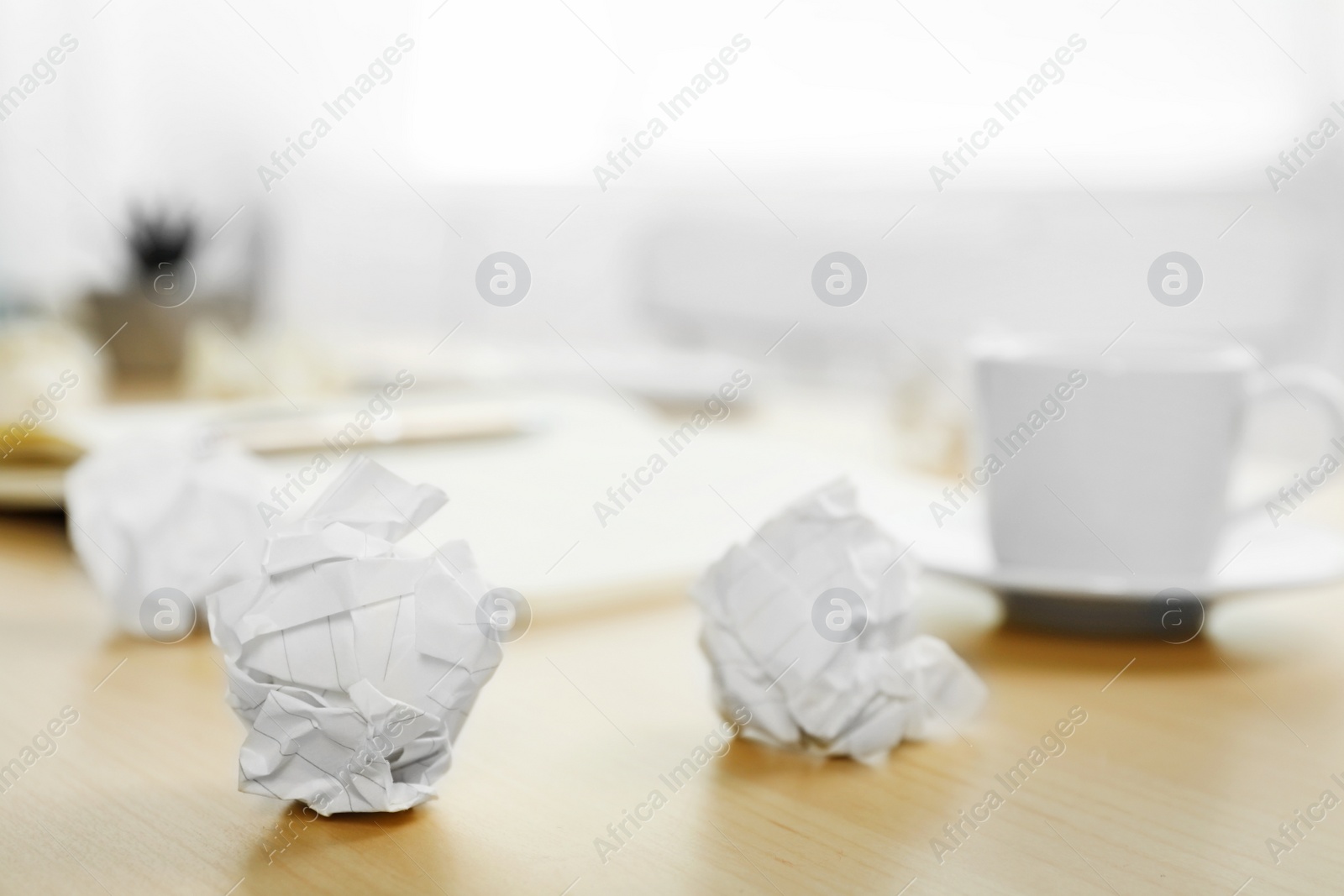 Photo of Sheets of crumpled paper and cup on wooden table, space for text